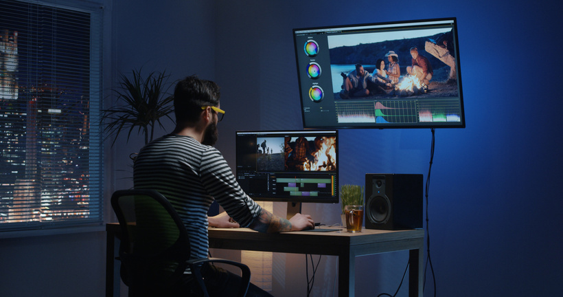 Young man sitting back and editing video inside a room